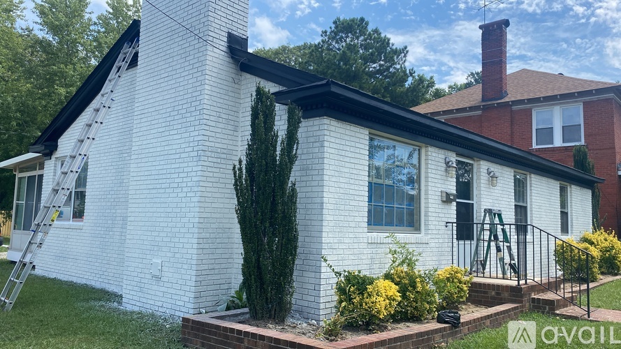 A white house with a black roof and a brick chimney.