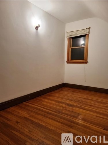 A room with wooden floors and a window with blinds.
