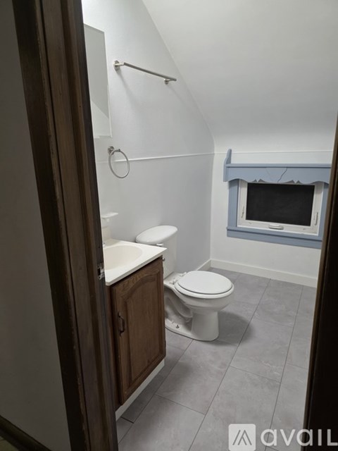 A small bathroom with a toilet, sink, and a window.