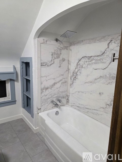A bathroom with a marble wallpaper and a bathtub.