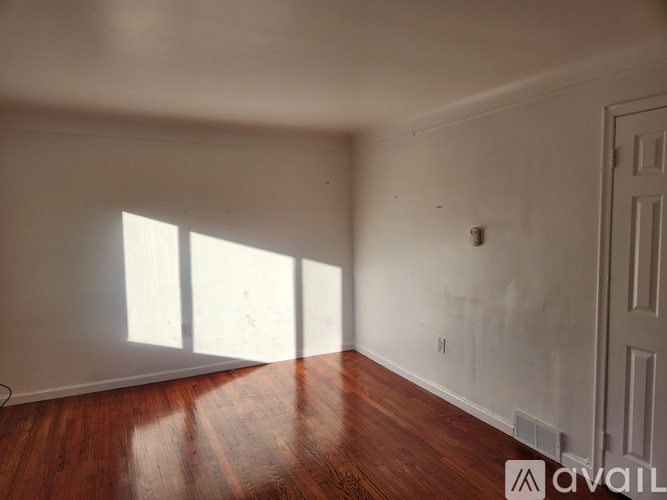 A room with wooden floors and white walls, with a door on the right side.