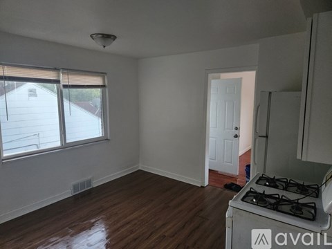 A room with a gas stove and a window with blinds.