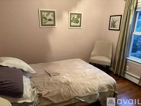 A bedroom with a bed, chair, and pictures on the wall.