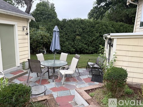 A patio with a table and chairs and a blue umbrella.