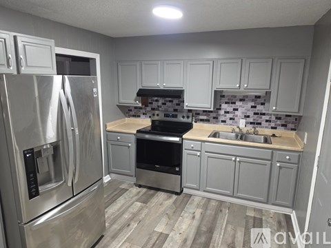 A kitchen with a stainless steel refrigerator and a black stove top oven.