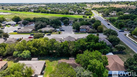 A bird's eye view of a suburban neighborhood with houses, trees, and a road.
