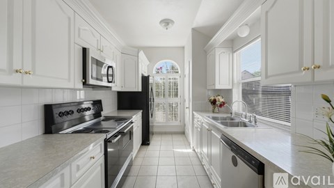 A kitchen with white cabinets and black appliances.