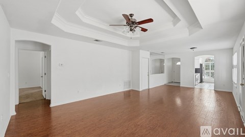 A spacious room with wooden floors and a ceiling fan.