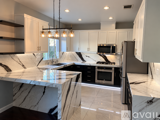 A modern kitchen with a marble countertop and stainless steel appliances.