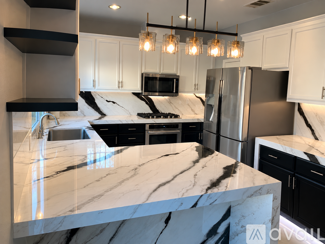 A kitchen with a marble countertop and black cabinets.