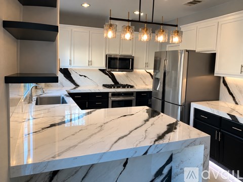 A kitchen with a marble countertop and black cabinets.