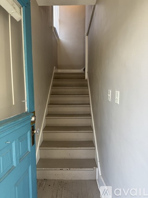 A staircase with a blue door on the left.
