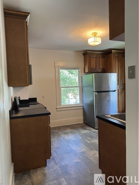 A kitchen with wooden cabinets and a stainless steel refrigerator.