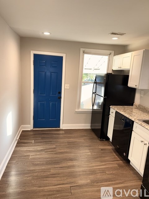 A kitchen with a black fridge and white cabinets.