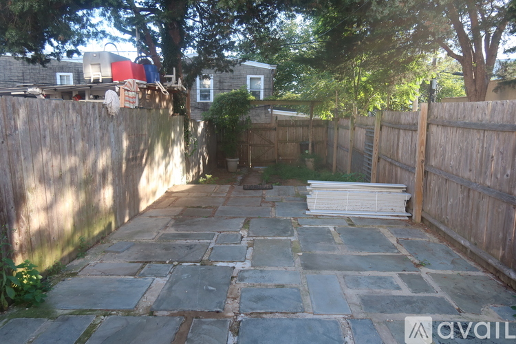 A backyard with a stone pathway and a wooden fence.