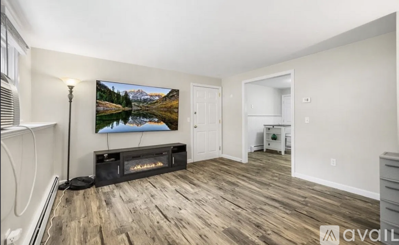 A living room with a large painting of a lake and mountains on the wall.