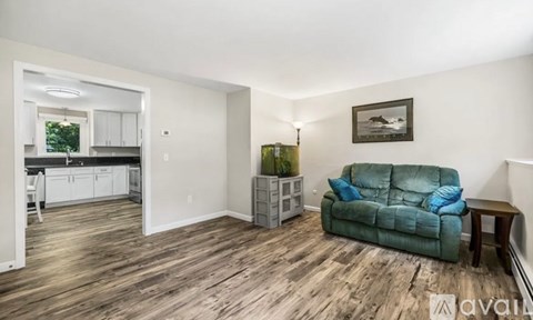 A living room with a green couch and a painting on the wall.