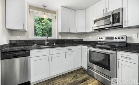 A kitchen with white cabinets and black countertops.