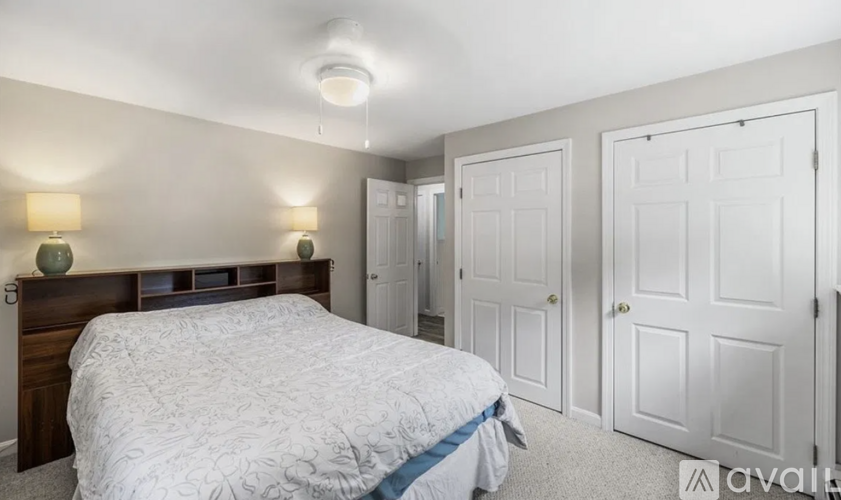A bedroom with a bed, two lamps, and three doors.