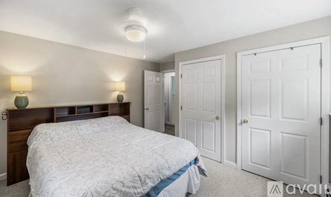 A bedroom with a bed, two lamps, and three doors.