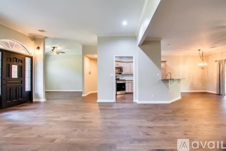 A spacious living room with a dark wood floor and white walls.