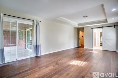 A spacious room with wooden flooring and white walls.