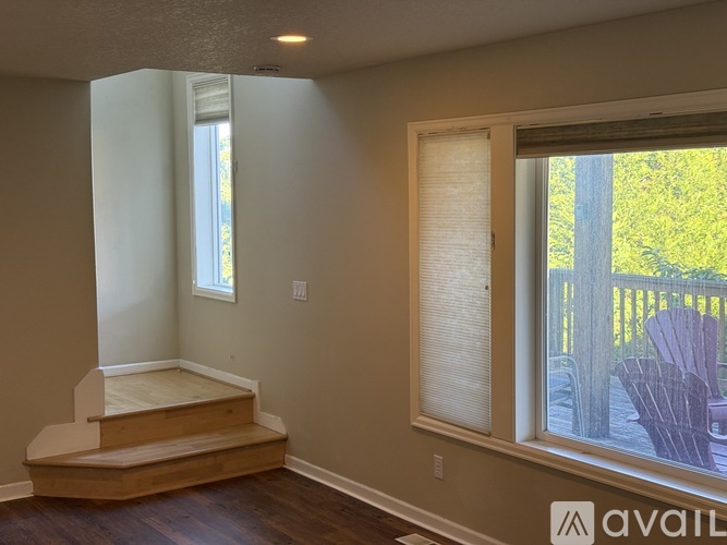 A room with a window and a wooden staircase.