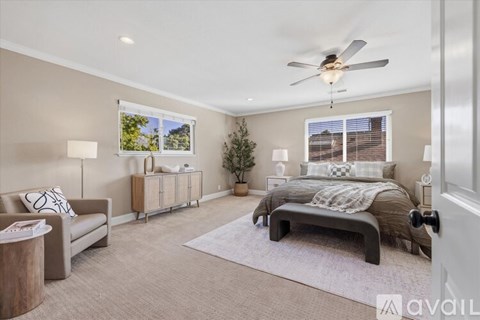 A well-lit bedroom with a bed, couch, and a ceiling fan.