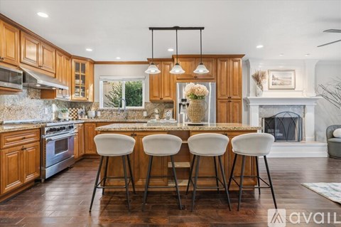 A kitchen with wooden cabinets and a marble backsplash.