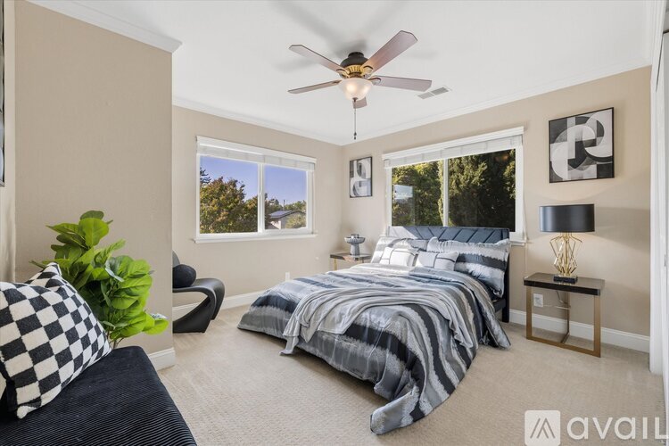 A bedroom with a bed, a chair, and a ceiling fan.