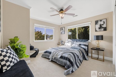A bedroom with a bed, a chair, and a ceiling fan.