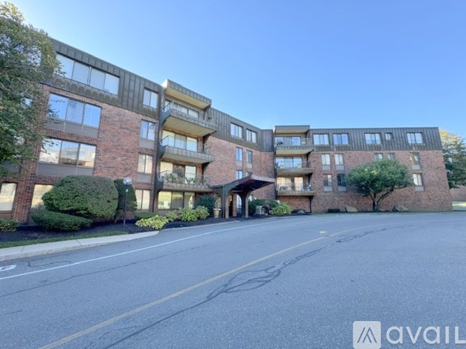 A large brick apartment building with multiple balconies and a driveway in front.