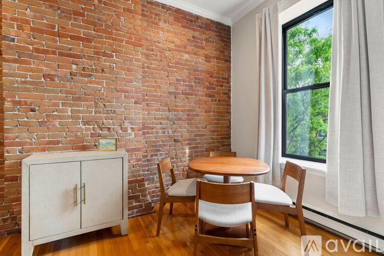 A room with a brick wall and a wooden table with chairs.