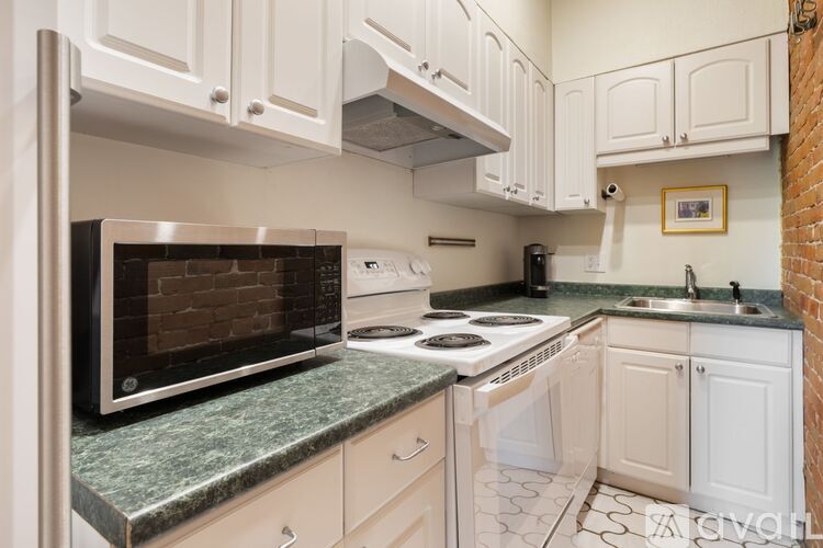 A kitchen with white cabinets and a brick wall.