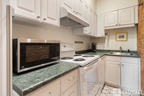A kitchen with white cabinets and a brick wall.