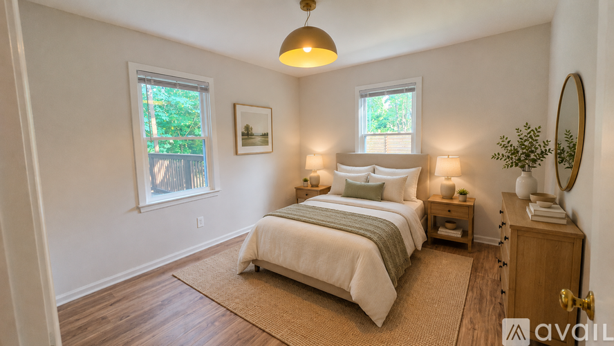 A bedroom with a large bed, a nightstand, and a window with a view of trees.