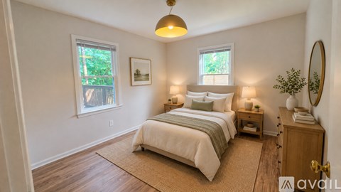 A bedroom with a large bed, a nightstand, and a window with a view of trees.