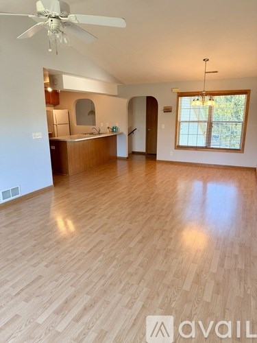 A spacious room with wooden flooring and a ceiling fan.