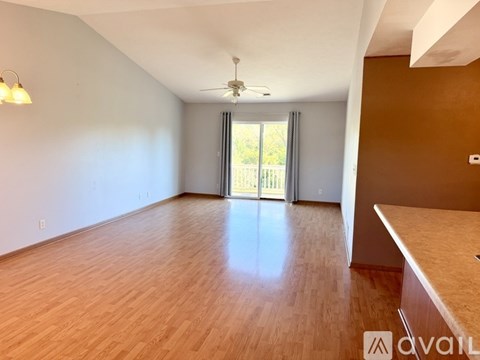 A spacious room with wooden flooring and a ceiling fan.