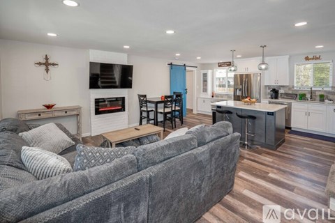 A grey couch sits in a living room with a fireplace and a television.