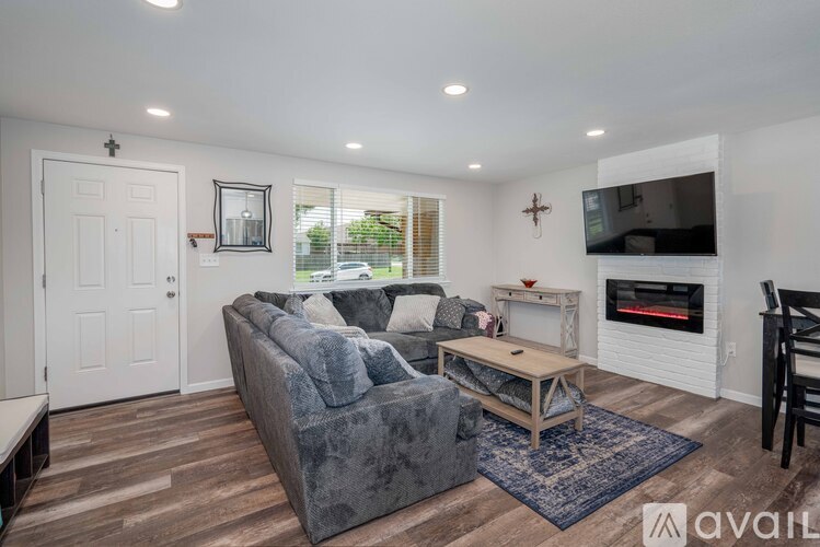 A living room with a grey couch and a fireplace.