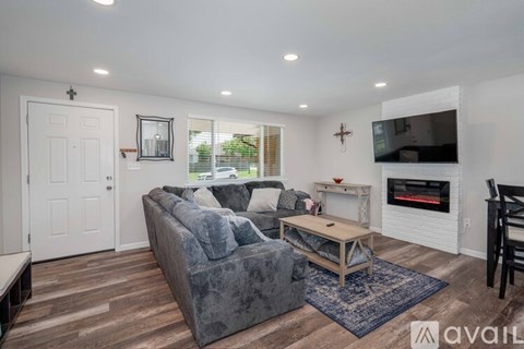 A living room with a grey couch and a fireplace.