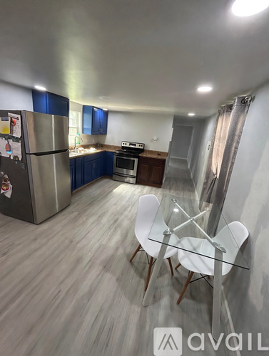 A kitchen with a refrigerator, stove, and a dining table with chairs.