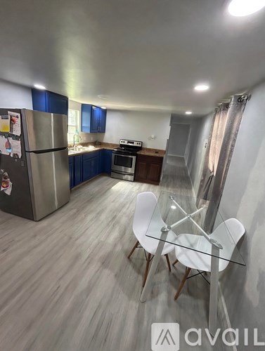 A kitchen with a refrigerator, stove, and a dining table with chairs.