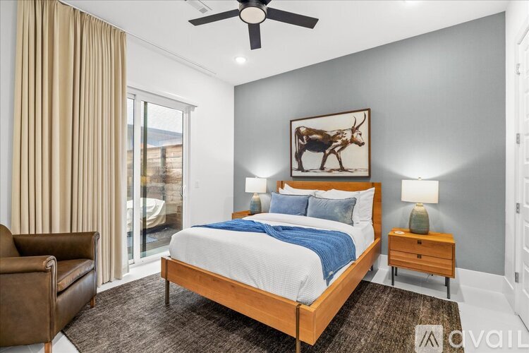A bedroom with a large bed, a ceiling fan, and a painting of a cow.