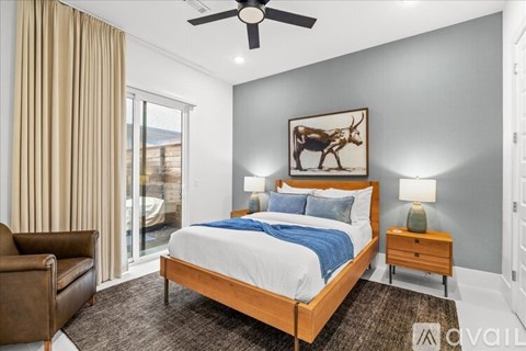 A bedroom with a large bed, a ceiling fan, and a painting of a cow.