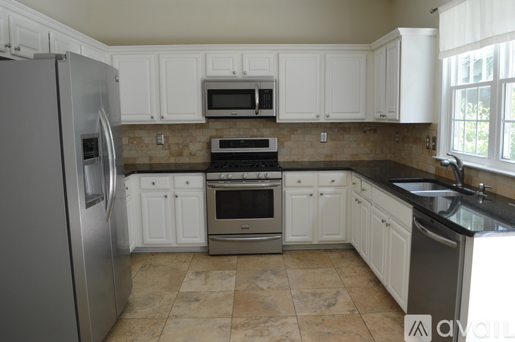 A kitchen with white cabinets and a tiled backsplash.