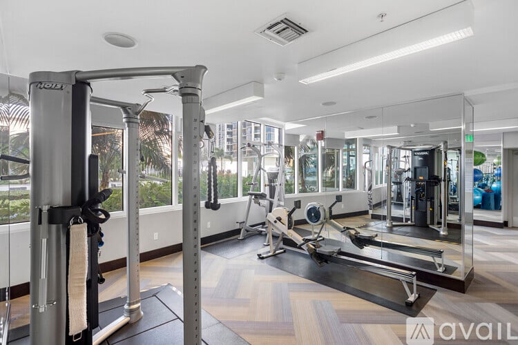 A gym with a variety of equipment including a squat rack, a leg press machine, and a treadmill.