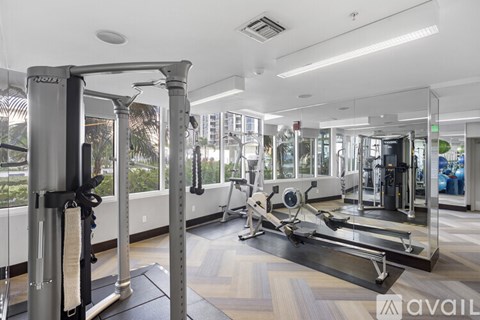 A gym with a variety of equipment including a squat rack, a leg press machine, and a treadmill.