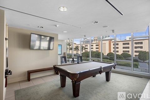 A room with a pool table and a television.